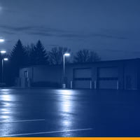 A sealed parking lot at dusk with lit maintenance bays under a Kardin navy gradient overlay.