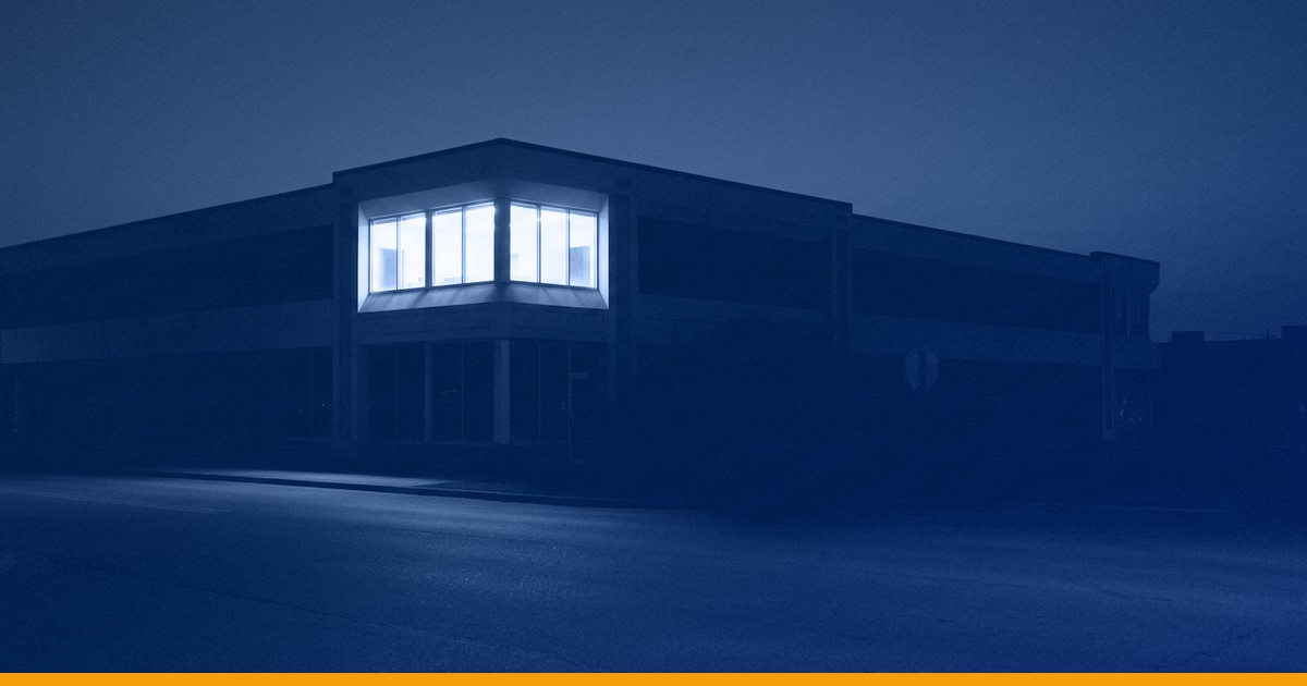 A commercial building at night with a single lit corner office, under a Kardin navy gradient overlay.