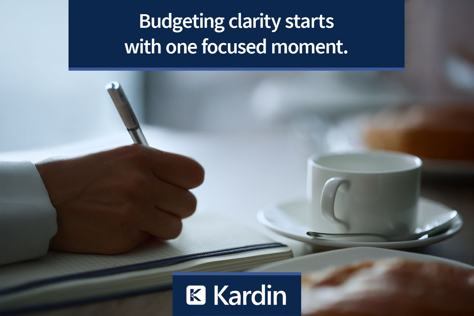 Close-up of a person writing in a notebook beside a cup of coffee and a pastry in soft morning light. The scene evokes focus, reflection, and clarity—mirroring the quiet discipline behind Kardin’s budgeting and reforecasting approach.